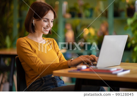 Happy brunette young woman freelancer working from cafe Happy brunette young woman freelancer working from cafe 99128045