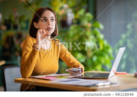 Pensive woman independent contractor working at cafe, using laptop, phone Pensive woman independent contractor working at cafe, using laptop, phone 99128046