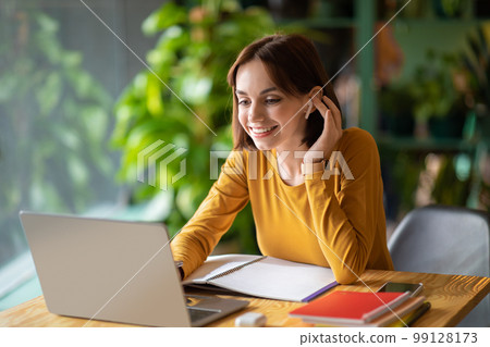 Cheerful young woman attending online business meeting, cafe interior 99128173