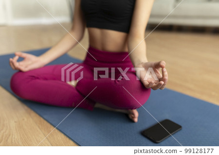 Sports, meditation, online training at home. Lady practicing yoga on mat with smartphone with blank screen, mockup 99128177