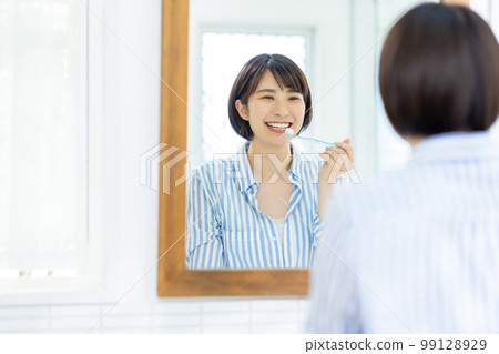A young woman brushing her teeth 99128929