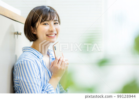 A young woman operating a smartphone 99128944