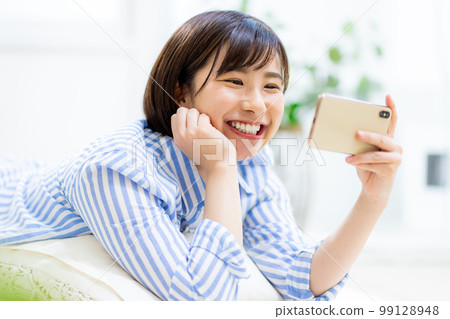 A woman looks at her smartphone while sleeping A woman looks at her smartphone while sleeping 99128948