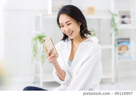 一個操作智能手機的年輕女子 99128997
