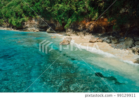 Aerial view of coastline with turquoise ocean and tropical beach under rocks. 99129911