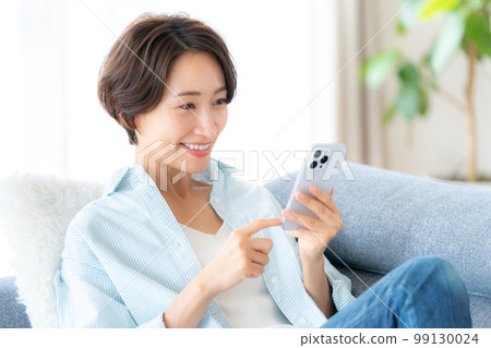 Middle woman operating a smartphone in the room 99130024