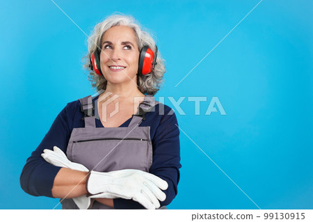 Dreamy mature female carpentry worker with tools and work uniform Dreamy mature female carpentry worker with tools and work uniform 99130915