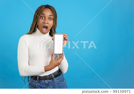 Surprised african woman showing a mobile phone screen Surprised african woman showing a mobile phone screen 99130971