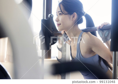 Young woman doing barbell squats in fitness gym 99131048
