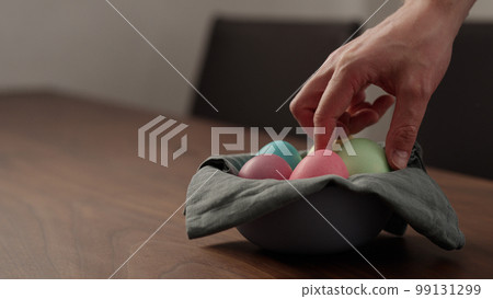 Man hand put easter egg in a bowl on walnut table Man hand put easter egg in a bowl on walnut table 99131299