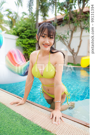 Asian young sexy woman wearing a yellow bikini Playing in the pool at Pool Villa 99131394