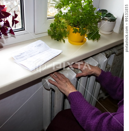 Woman holding cash in front of heating radiator. Payment for heating in winter. Selective focus. 99131855