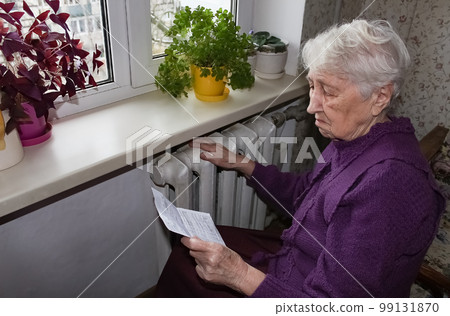 Woman holding cash in front of heating radiator. Payment for heating in winter. Selective focus. 99131870