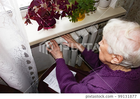 Woman holding cash in front of heating radiator. Payment for heating in winter. Selective focus. 99131877
