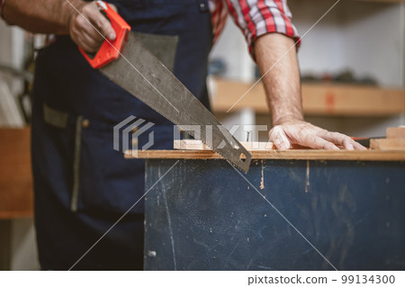 home builder working cutting wood panel with saw tool. diy wood workshop making furniture. home builder working cutting wood panel with saw tool. diy wood workshop making furniture. 99134300