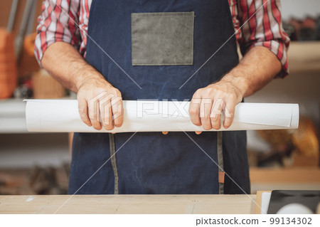 closeup hand of builder with floor plan paper roll for smart home improvement project concept 99134302