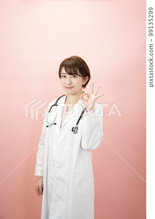 Female doctor smiling with pink back and ok sign 99135299