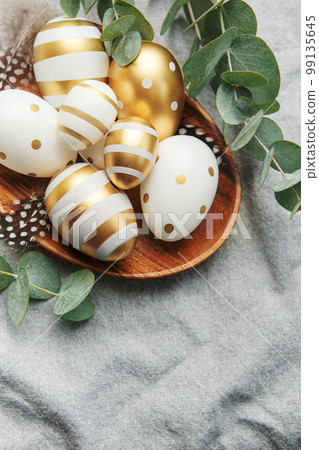 Easter decor. Colored Easter eggs on a wooden plate on the table. Easter decor. Colored Easter eggs on a wooden plate on the table. 99135645