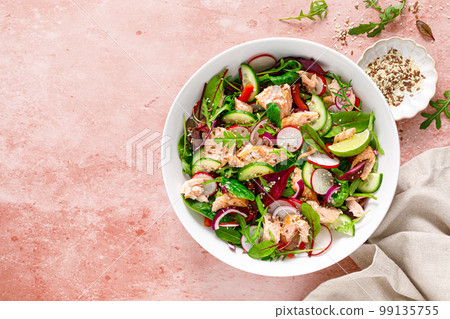 Salmon salad bowl with fresh radish, cucumber, red onion and green mixed leafy vegetables. Healthy diet food, lunch menu. Top view 99135755