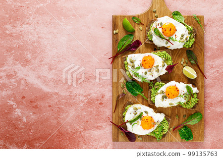 Egg and avocado toast, sandwiches with eggs and fresh greens. Healthy diet food. Top view 99135763
