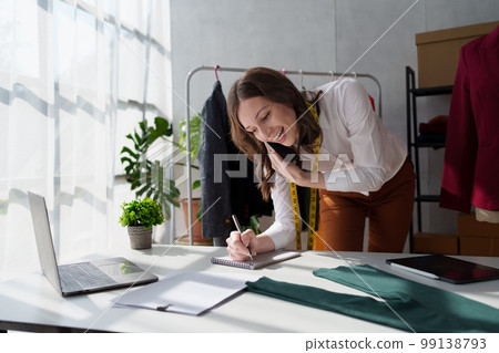 Beautiful young professional stylist working at design studio interior. fashion designer concept Beautiful young professional stylist working at design studio interior. fashion designer concept 99138793