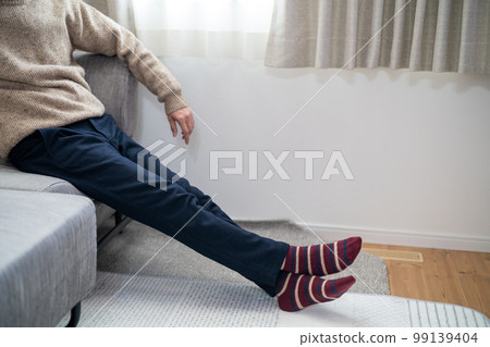 A man sits on a sofa in the living room 99139404