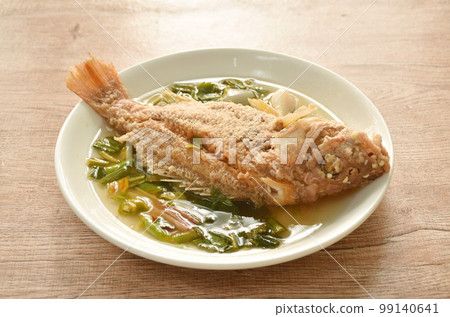 spicy boiled fried red bass fish and  herb in tom yum soup on plate 99140641