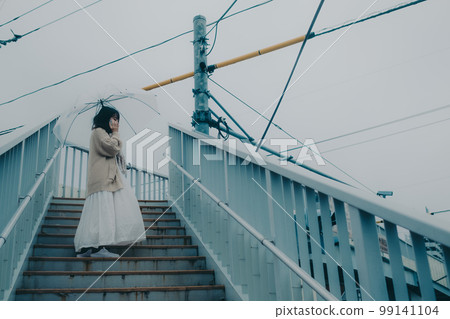 一名女子在立交橋上打傘並手持智能手機的照片 99141104