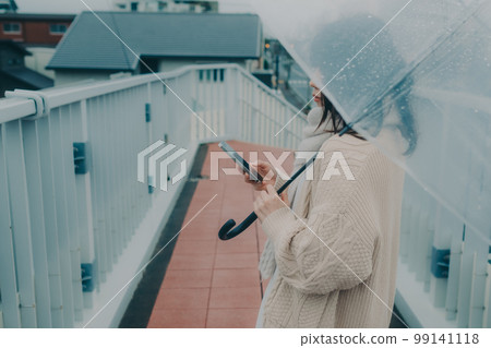 一名女子在立交橋上打傘並手持智能手機的照片 99141118