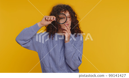 Investigator researcher woman with magnifying glass near face, looking into camera with big zoom eye Investigator researcher woman with magnifying glass near face, looking into camera with big zoom eye 99141427