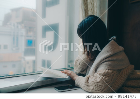Photo of a woman reading in a coffee shop 99141475
