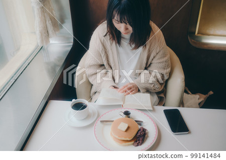 Photo of a woman reading in a coffee shop Photo of a woman reading in a coffee shop 99141484