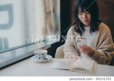 Photo of a woman reading in a coffee shop Photo of a woman reading in a coffee shop 99141701