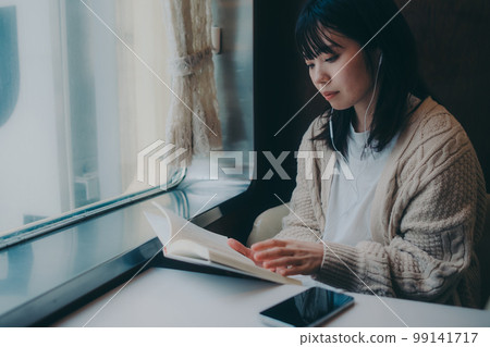 Photo of a woman reading in a coffee shop 99141717