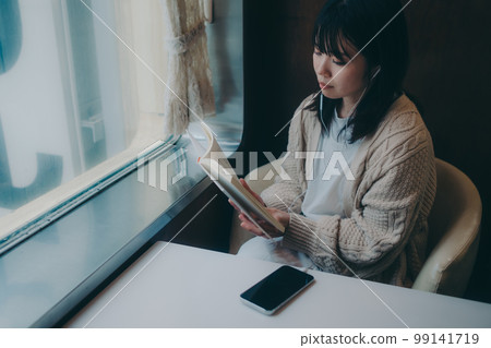Photo of a woman reading in a coffee shop 99141719