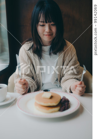 Photo of a woman eating hot cakes at a coffee shop Photo of a woman eating hot cakes at a coffee shop 99142069