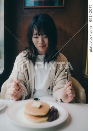 Photo of a woman eating hot cakes at a coffee shop 99142073