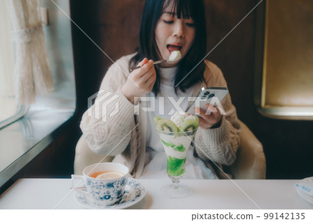 Photo of a woman eating a parfait at a coffee shop 99142135