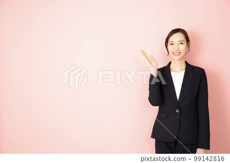 A woman wearing a navy suit with a pink back and raising her right hand 99142816