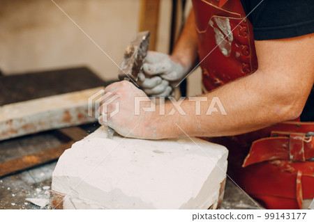 Man sculptor creates sculpt bust gypsum human woman sculpture with hammer. Statue craft creation workshop. Man sculptor creates sculpt bust gypsum human woman sculpture with hammer. Statue craft creation workshop. 99143177