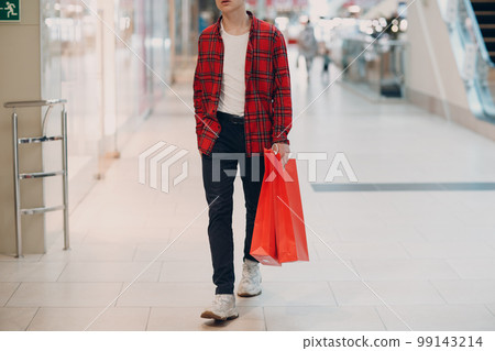A young man goes shopping mall store with shopping bags. A young man goes shopping mall store with shopping bags. 99143214