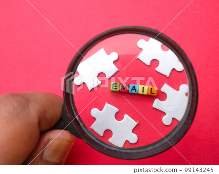 Hand holding magnifying glass with colored dice word EMAIL. 99143245