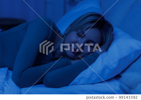 Sleeping young woman lying on pillow in bed at night Sleeping young woman lying on pillow in bed at night 99143392