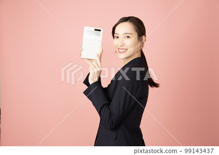 A woman with a white calculator wearing a navy suit with a pink back A woman with a white calculator wearing a navy suit with a pink back 99143437