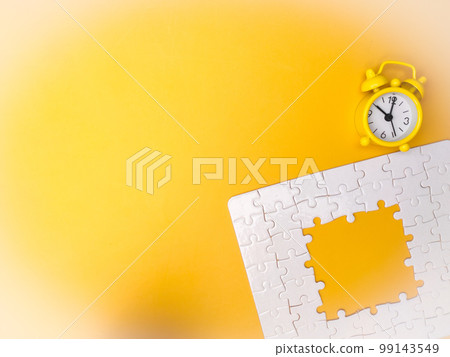 Concept yellow alarm clock and puzzle on yellow background 99143549