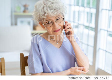 Senior woman making a phone call in the living room Senior woman making a phone call in the living room 99143718