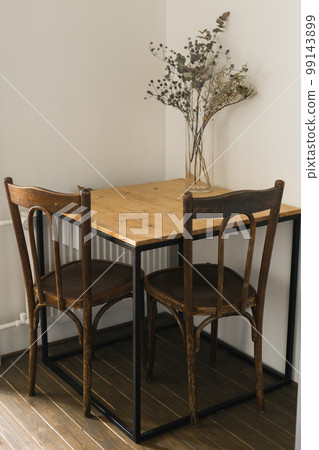 Dry plants in minimalistic glass jar. Vertical image of branch with dry leaves in stylish simple glass vase. Decoration and interior design 99143899