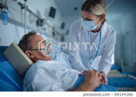 Young woman doctor talking to elderly patient with oxygen mask. 99144166
