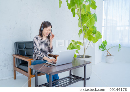 Woman working from home with headset and video chatting Woman working from home with headset and video chatting 99144178