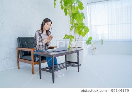 Woman working from home with headset and video chatting Woman working from home with headset and video chatting 99144179